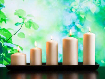 white candles on wood table and natural green backgroundの写真素材