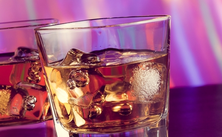 whiskey glass with ice on bar table on warm atmosphere lounge bar conceptの写真素材