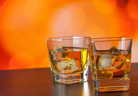 whiskey glass with ice on bar table on warm atmosphere lounge bar conceptの写真素材