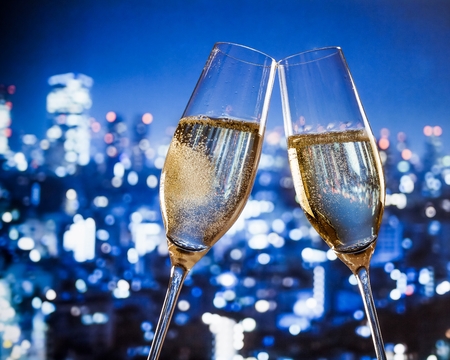 champagne flutes with golden bubbles make cheers on blue city night lights background with space for textの写真素材