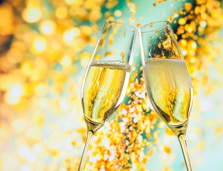 a pair of champagne flutes with golden bubbles make cheers on golden light background with space for textの写真素材