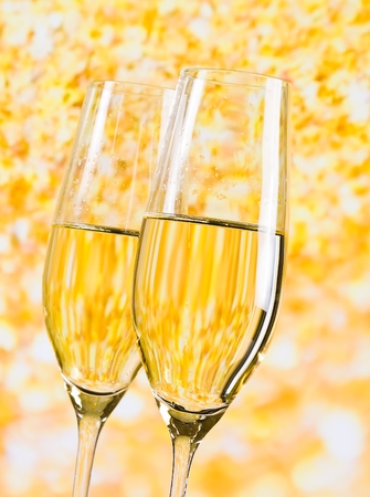 two champagne flutes on golden light backgroundの写真素材