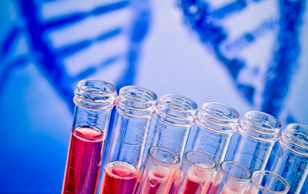 closeup of test tubes with red liquid on blue blur abstract dna backgroundの写真素材