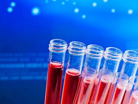 closeup of test tubes with red liquid in laboratory on blue light tint backgroundの写真素材