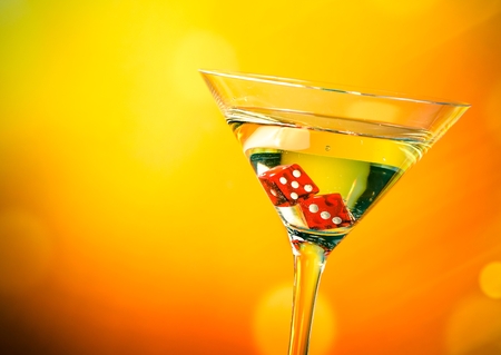 red dice in the cocktail glass on golden bokeh backgroundの写真素材