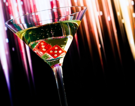 red dice in the cocktail glass on colorful gradient background with space for textの写真素材