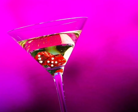 red dice in the cocktail glass on violet background with space for textの写真素材