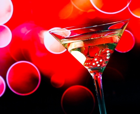 red dice in the cocktail glass on red bokeh backgroundの写真素材