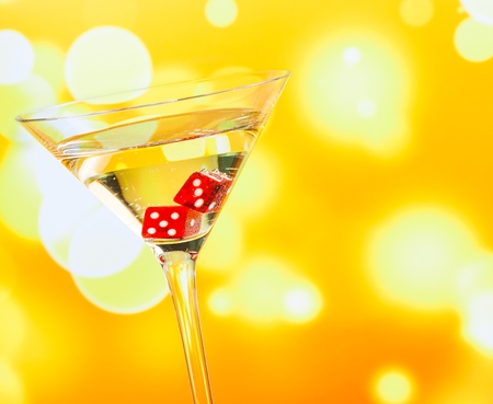 red dice in the cocktail glass on golden bokeh backgroundの写真素材