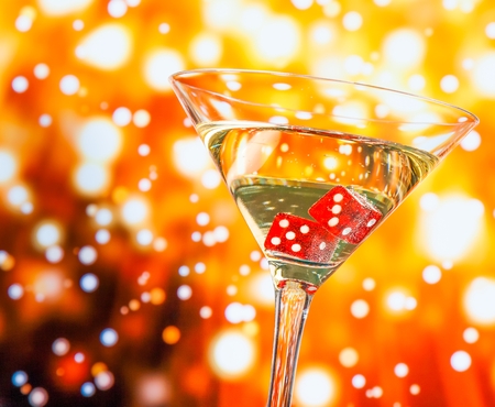 red dice in the cocktail glass on golden bokeh backgroundの写真素材