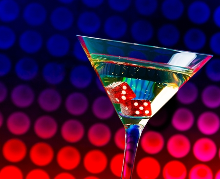 red dice in the cocktail glass on colorful gradient bokeh backgroundの写真素材