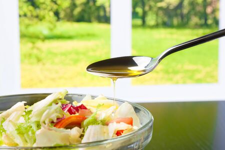 spoon with olive oil on italian fresh salad on window background diet conceptの写真素材