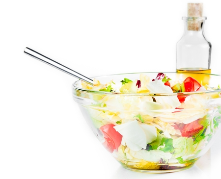 Italian fresh salad with fork isolated in front of olive oil bottle on white background diet conceptの写真素材