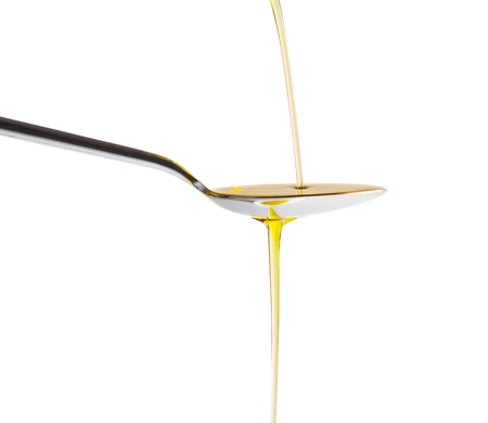 Extra virgin olive oil pouring over a spoon isolated on white background with a space for textの写真素材