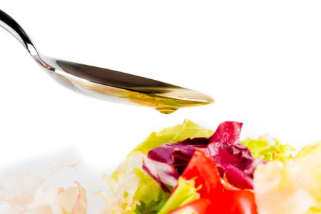 spoon with olive oil on italian fresh salad on white background nutrition conceptの写真素材