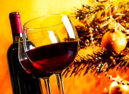 two red wine glasses near bottle against christmas tree background, christmas atmosphereの写真素材