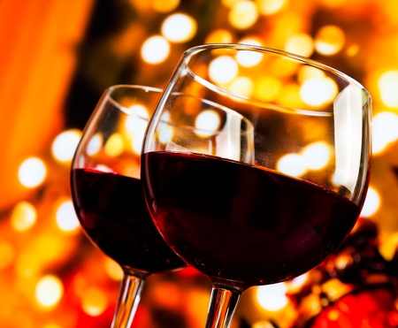 two red wine glasses against tree of bokeh lights background, christmas atmosphereの写真素材