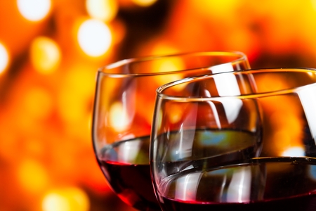 two red wine glasses against colorful unfocused lights background, festive and fun conceptの写真素材
