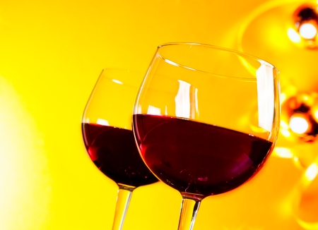 two red wine glasses against golden lights background, festive and fun conceptの写真素材