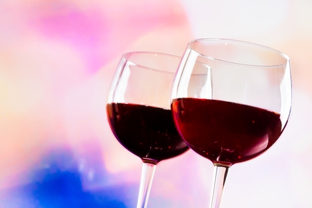 red wine glasses against colorful unfocused lights background, festive and fun conceptの写真素材