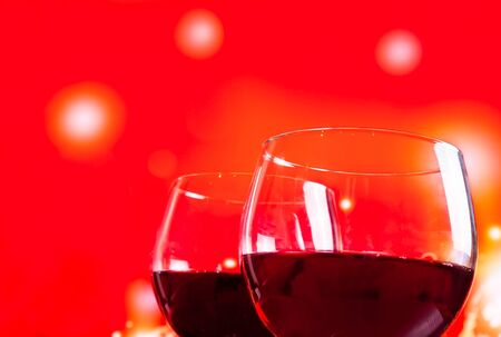 two red wine glasses near the bottle against red lights background, festive and fun conceptの写真素材