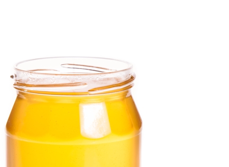 closeup of opened honey jar isolated on white backgroundの写真素材