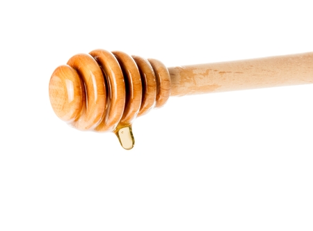 wooden honey dipper with drop honey, isolated on white backgroundの写真素材