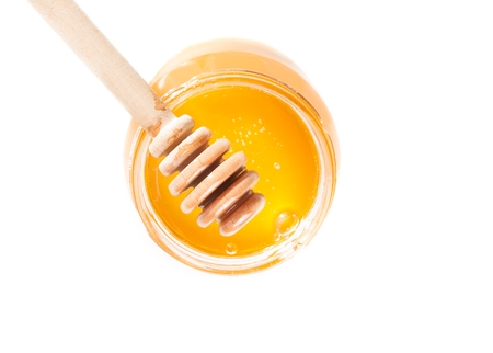 top of view of opened honey jar with wooden honey dipper on top, isolated on white backgroundの写真素材