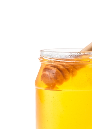 opened honey jar with wooden honey dipper inside, isolated on white backgroundの写真素材