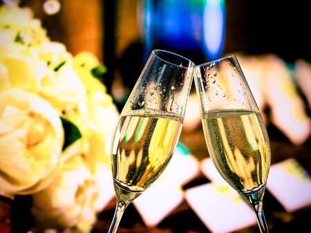 champagne flutes with golden bubbles make cheers on wedding flowers backgroundの写真素材