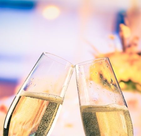 champagne flutes with golden bubbles make cheers on flowers background wedding and valentine day conceptの写真素材