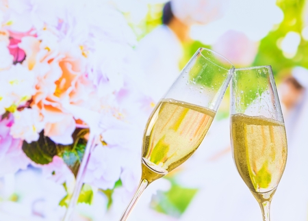 champagne flutes with golden bubbles make cheers on wedding flowers backgroundの写真素材