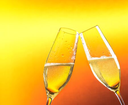 two flutes of champagne with golden bubbles and space for text against golden backgroundの写真素材
