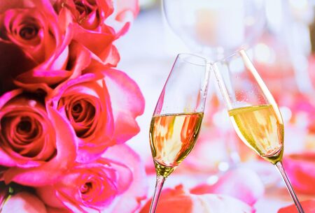 champagne flutes with golden bubbles make cheers on wedding roses flowers backgroundの写真素材