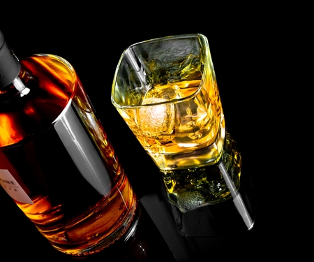 top of view of whiskey with ice in glass on black background, with reflectionの写真素材