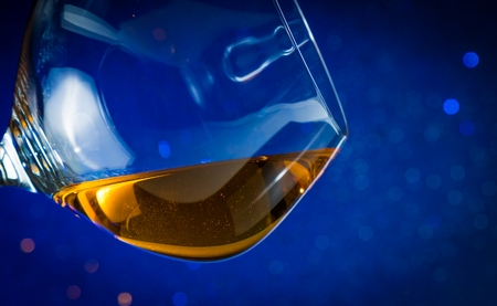 snifter of brandy in elegant glass with space for text on blue bokeh backgroundの写真素材
