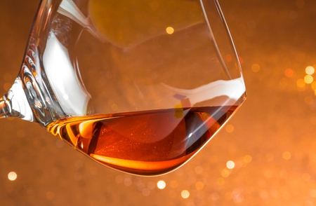 snifter of brandy in elegant glass with space for text on golden bokeh backgroundの写真素材