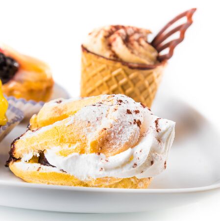 delicious little cream cake near cake with chocolate and fruit on white background