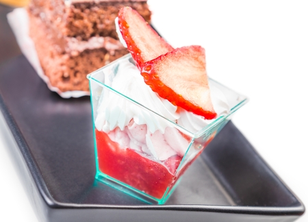 delicious strawberry cake with cream in front of little chocolate and coffee cakes on blackの写真素材