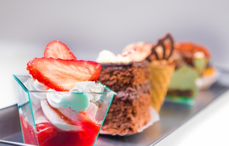 delicious strawberry cake with cream in front of little chocolate and coffee cakes on black dishの写真素材