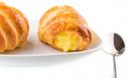delicious cannoli filled with cream near a spoon on white backgroundの写真素材
