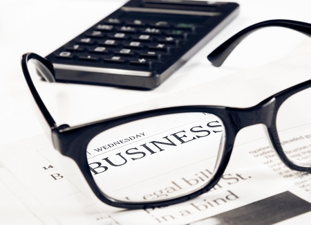 business word see through glasses lens on financial newspaper near calculator, business conceptの写真素材