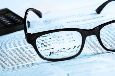 financial chart and graph currencies see through glasses lens on financial newspaper, business conceptの写真素材