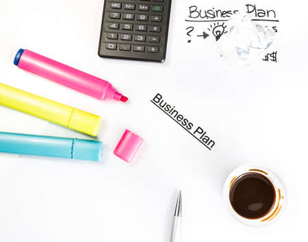 business plan words near highlighters, calculator and cup of coffee on white table, business conceptの写真素材