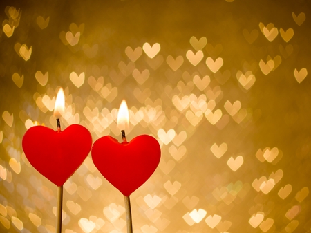 red hearts candles on golden hearts bokeh as background, valentine day and love conceptの写真素材