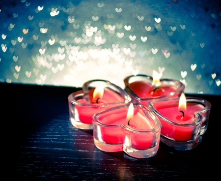 red burning heart shaped candles on blue hearts bokeh backgroundの写真素材