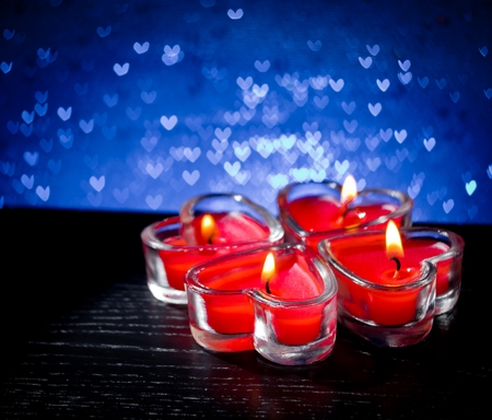 red burning heart shaped candles on blue hearts bokeh backgroundの写真素材