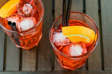 top of view of glasses of spritz aperitif aperol red cocktail with orange slices and ice cubes on wood tableの写真素材