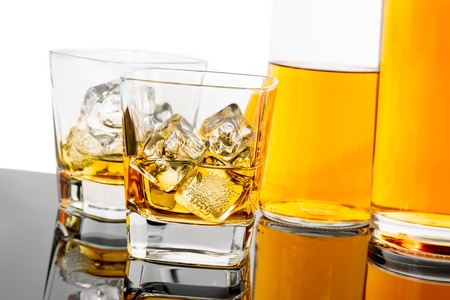 two glasses of whiskey near bottles on black background with reflection, time of relax with whisky