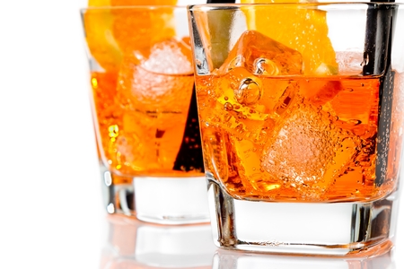 detail of two glasses of spritz aperitif aperol cocktail with orange slices and ice cubes on white backgroundの写真素材
